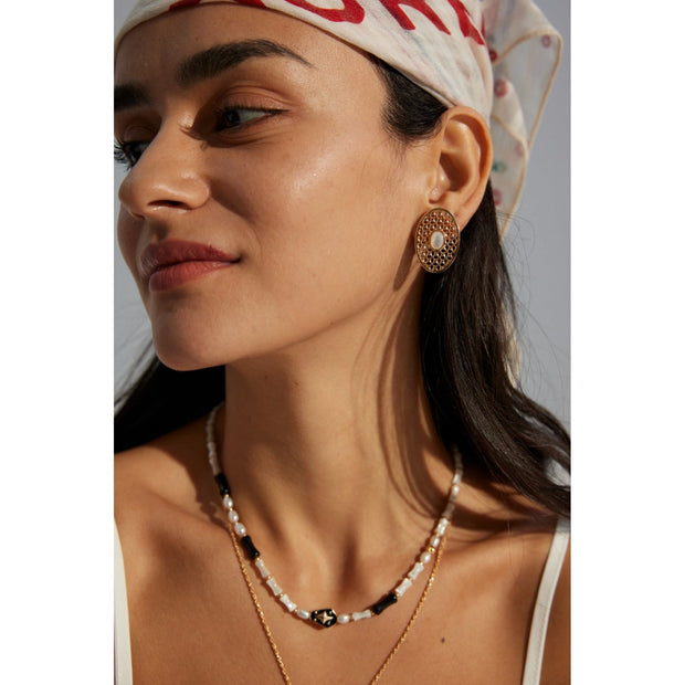 Gold oval pearl earrings with intricate lattice design on a white surface, ideal for vintage jewelry lovers, jewelry websites, and jewelry storage ideas. A perfect accessory for mature women hairstyles, earrings rings combinations, and showcasing gem jewelry or diamond and jewelry pieces.