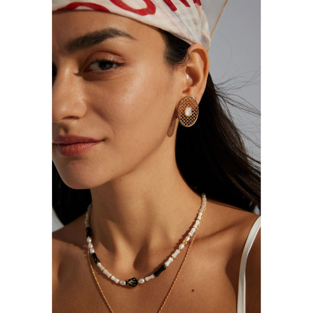 Gold oval pearl earrings with intricate lattice design on a white surface, ideal for vintage jewelry lovers, jewelry websites, and jewelry storage ideas. A perfect accessory for mature women hairstyles, earrings rings combinations, and showcasing gem jewelry or diamond and jewelry pieces.