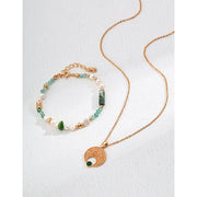 Gold pendant necklace with a textured circular design and green stone accent, ideal for jewelry storage, jewelry websites, vintage jewelry collections, and gifting.