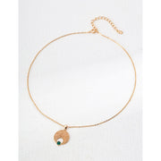 Gold pendant necklace with a textured circular design and green stone accent, ideal for jewelry storage, jewelry websites, vintage jewelry collections, and gifting.