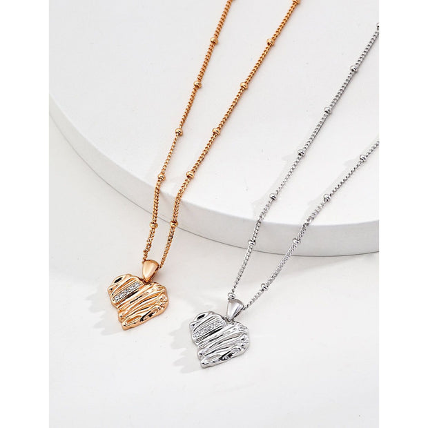 Gold and silver heart pendant necklaces with textured designs, perfect for jewelry storage, jewelry websites, vintage jewelry collections, and thoughtful gifting.