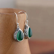 Vintage teardrop earrings with green gemstones and intricate silver detailing, perfect for jewelry storage, jewelry cleaning, and featuring on jewelry websites for vintage jewelry enthusiasts.